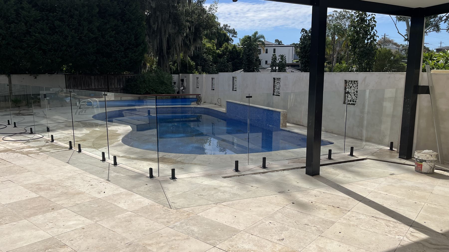 Frameless glass pool fence and travertine paving at a Sydney home, cleaned by ClearView